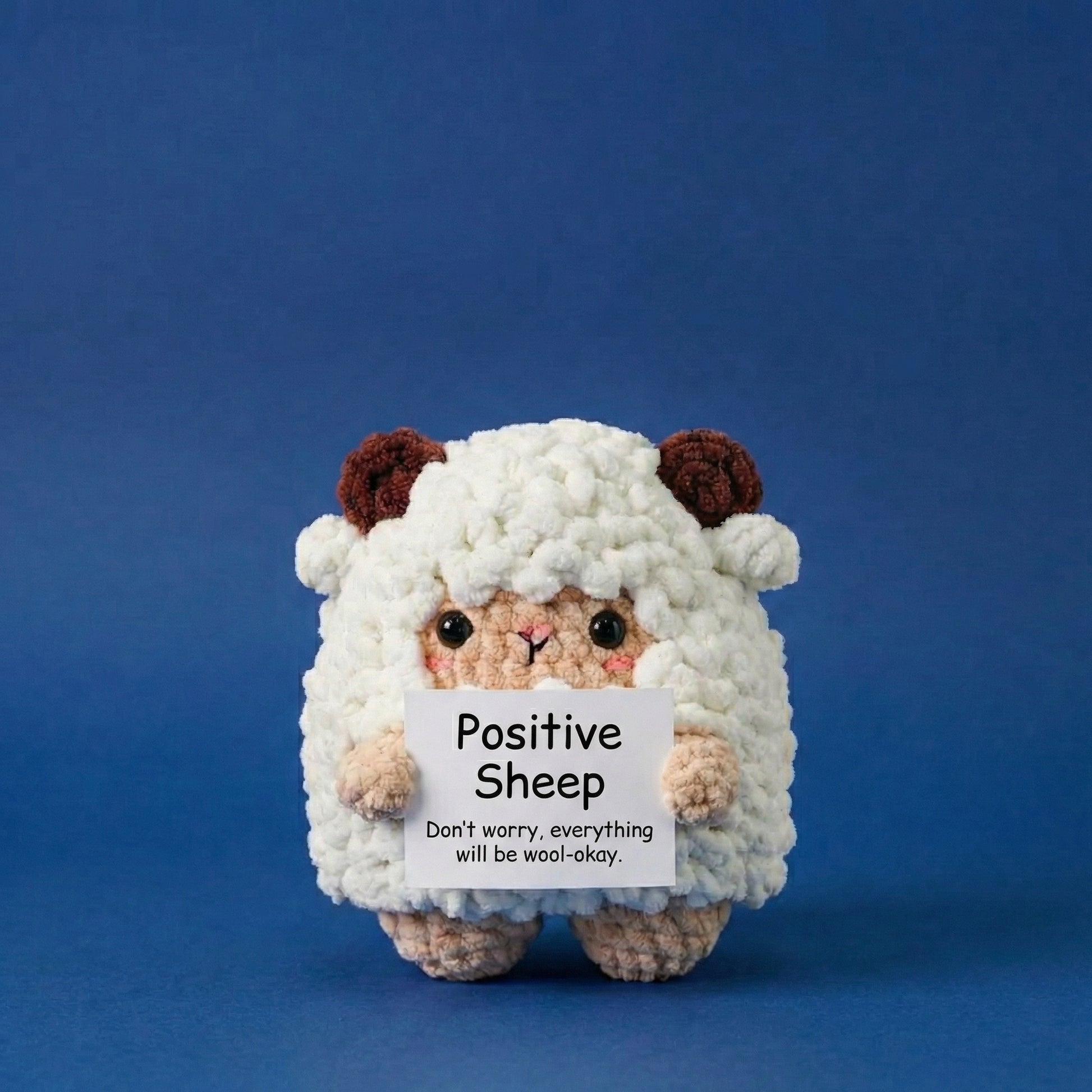 Plush toy sheep holding a sign with text on a blue background