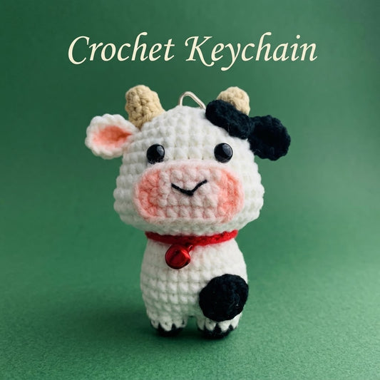 Crochet cow keychain by WoolyArtis featuring a cute amigurumi farm animal plush, perfect as a kawaii bag charm or purse accessory.